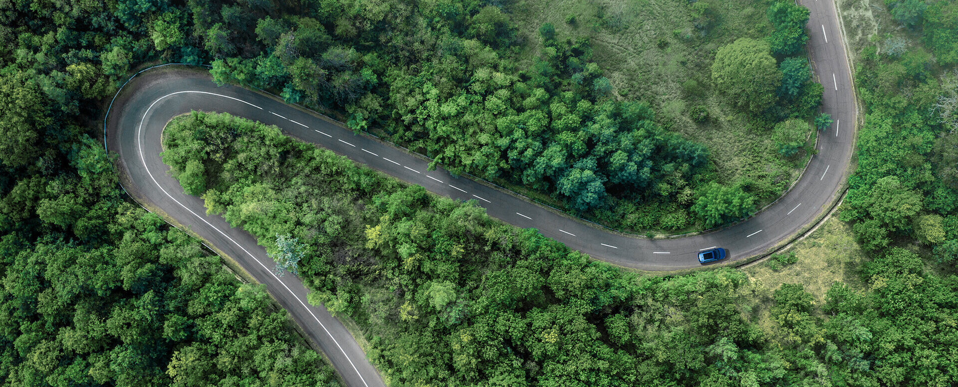 Ein Naturbild mit einer Straße und einem Auto, das dort langfährt