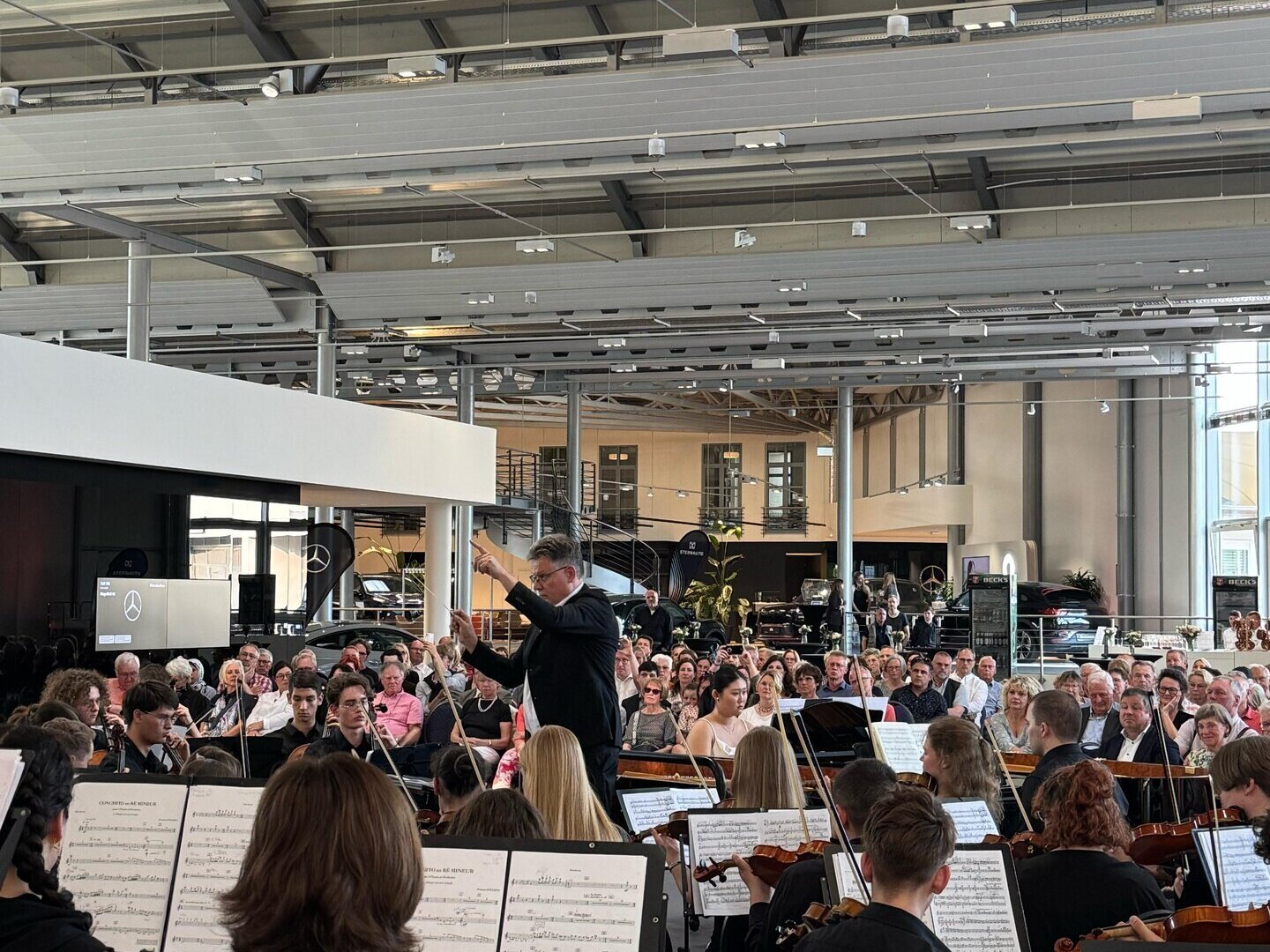 Ein Orchester und ein Dirigent spielen in einem Autohaus
