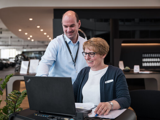 Mitarbeiter erklärt Mitarbeiterin am Laptop etwas
