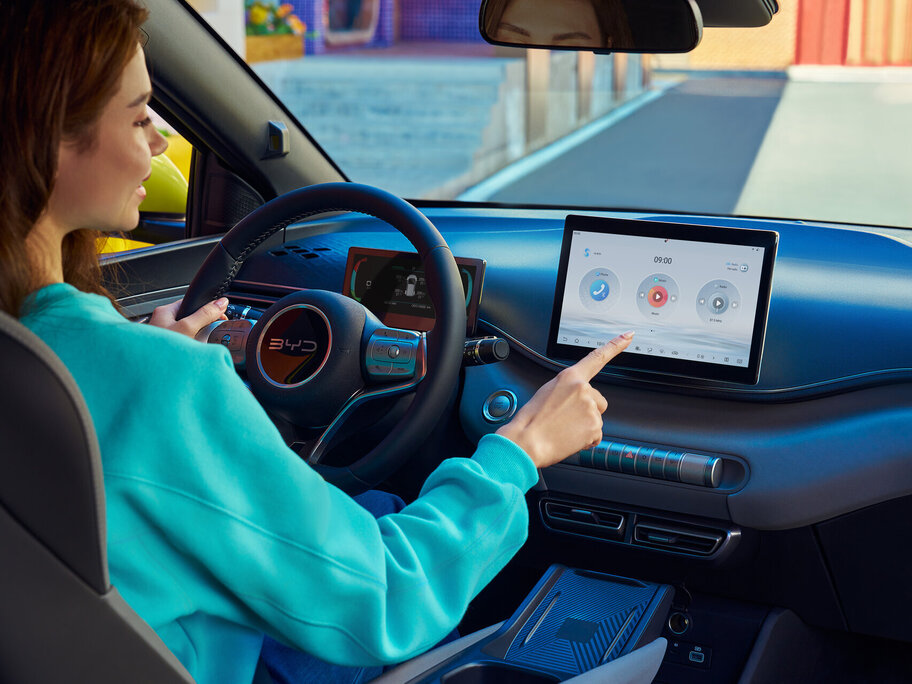 Im Interieur des BYD Dolphin Surf - zu sehen ist eine Frau die das Touchscreen bedient