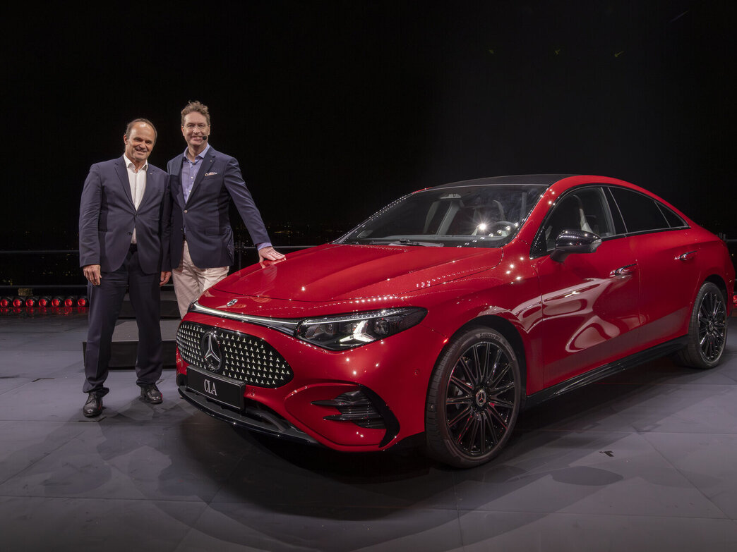 Roter Mercedes CLA mit schwarzem Kühlergrill und schwarzen Felgen, daneben zwei Männer in Anzügen auf dunklem Hintergrund.