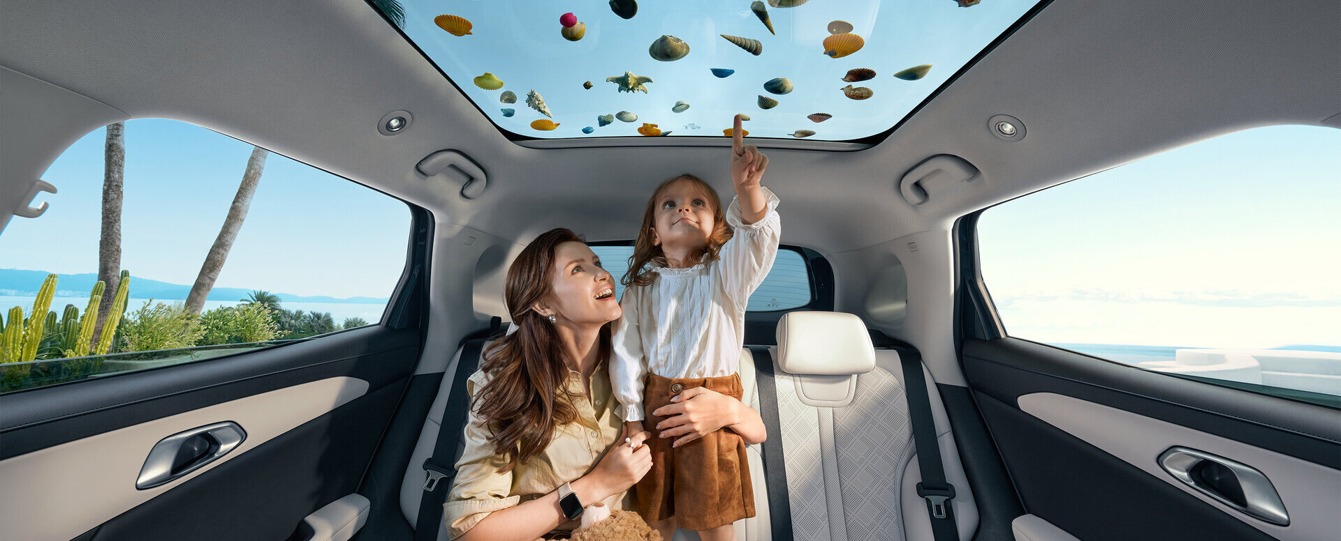 Frau und Kind sitzen auf der Rückbank eines Autos mit Panoramadach, das mit bunten Blättern bedeckt ist, Kind zeigt nach oben