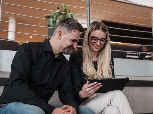 Kollege und Kollegin schauen gemeinsam auf ein Tablet