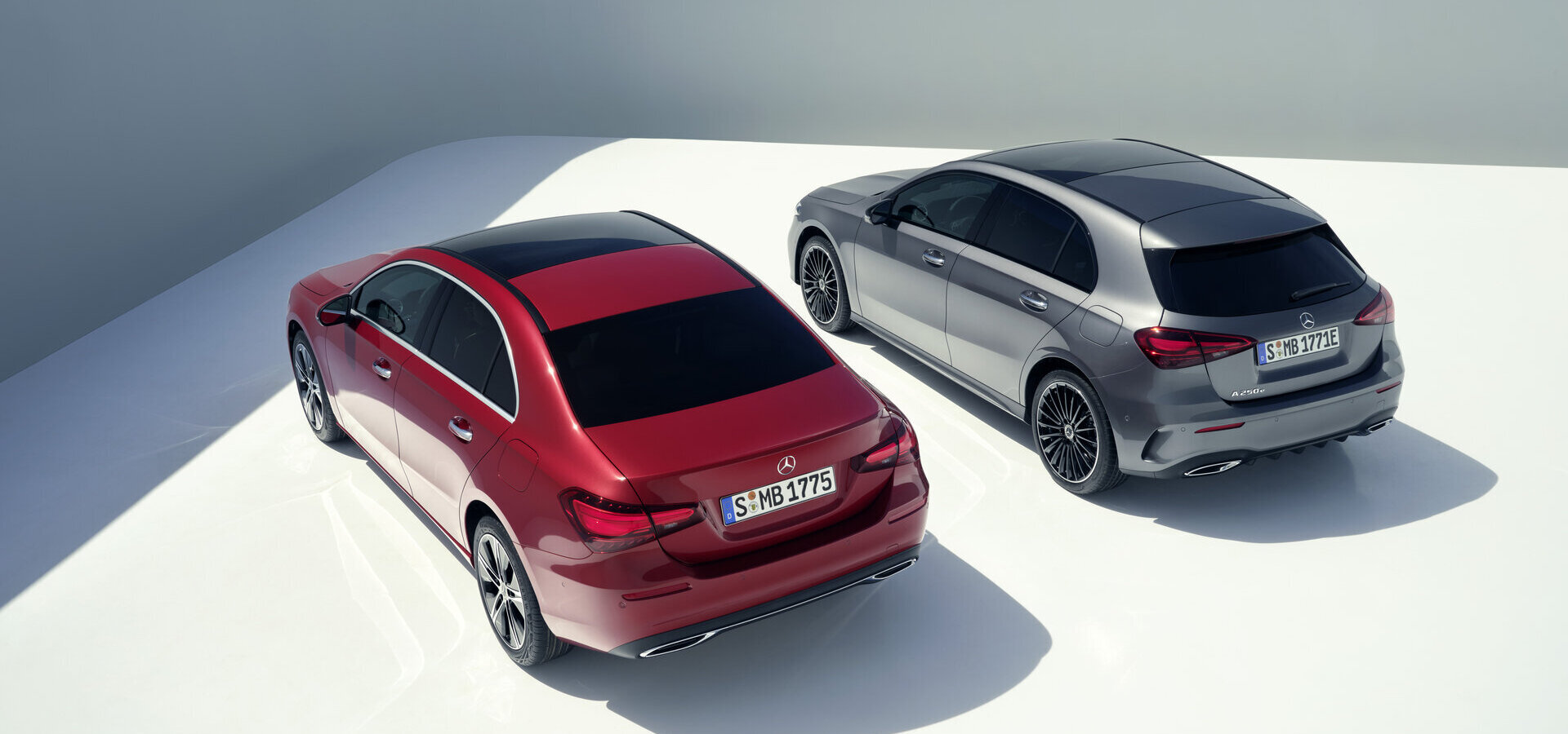 Zwei Mercedes Benz A 250e Hatchback in mountain grey und patagonia red in Heckansicht