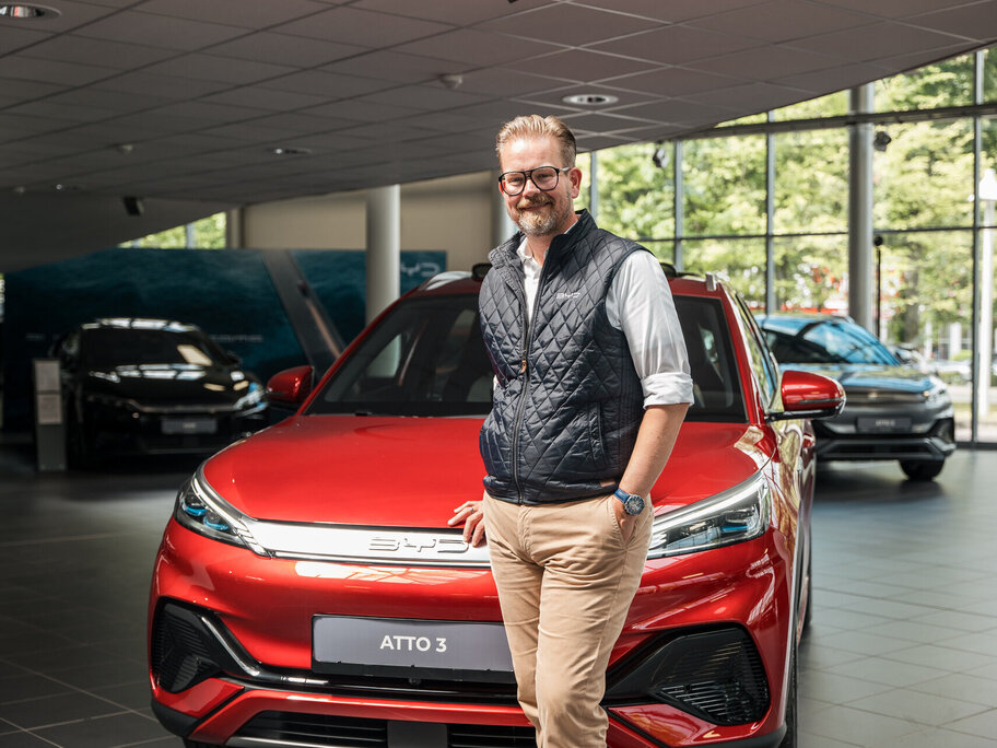 Ein Mann steht vor einem roten BYD