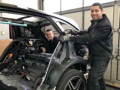 Zwei Azubis stehen an Autokarosserie 