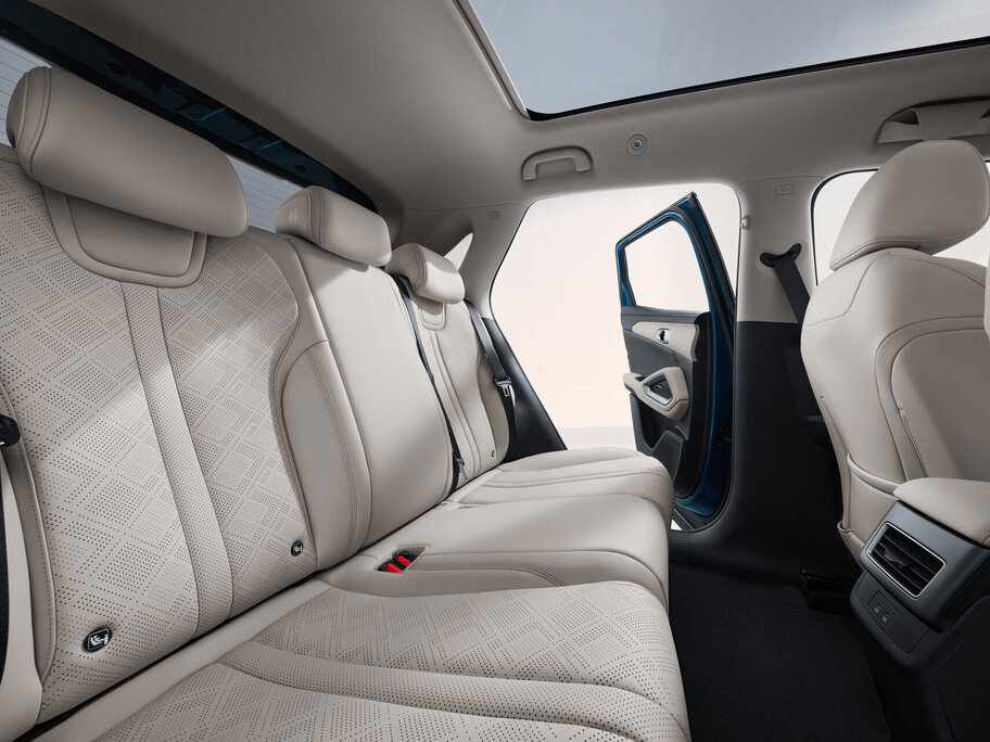 Innenraum eines Fahrzeugs mit beigen Rücksitzen und geöffneter hinterer Tür auf der Beifahrerseite