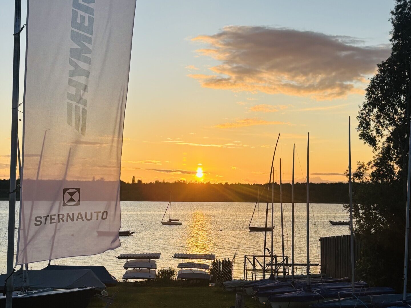 Ein See und ein Sonnenuntergang mit Booten und einer Hymer Fahne