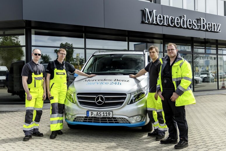 Vier Männer in Warnkleidung stehen vor einem Mercedes-Benz Transporter
