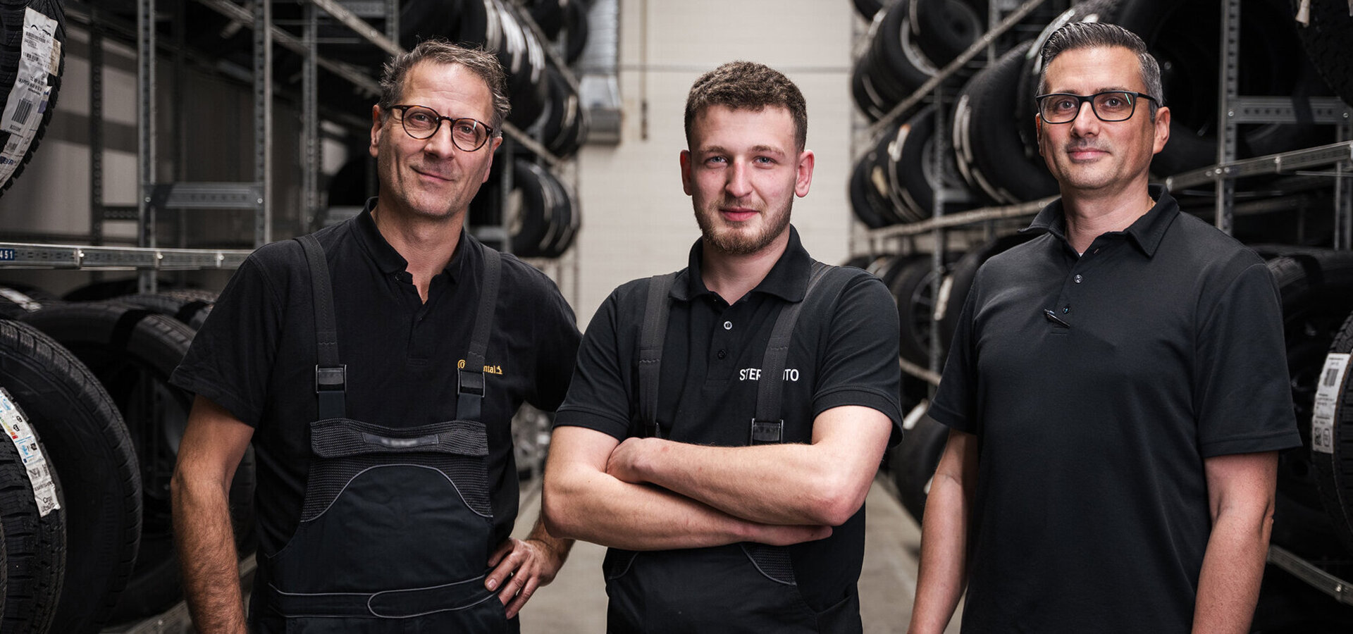 3 Mechaniker stehen im Reifenlager