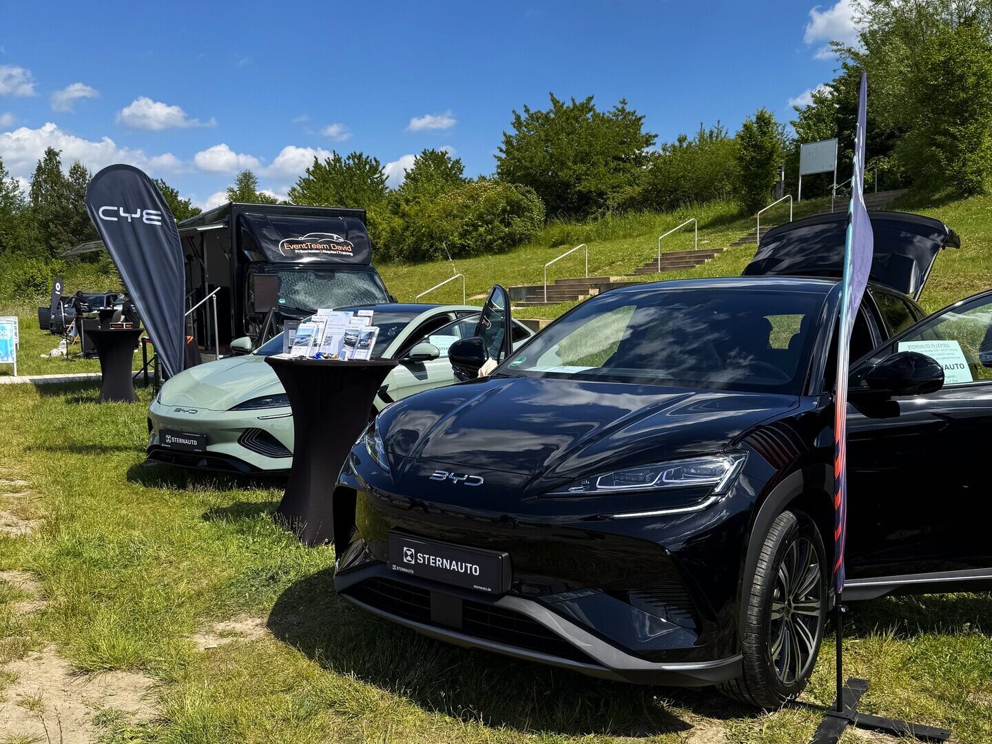 Draußen stehen zwei BYD Modelle in mintgrün und schwarz