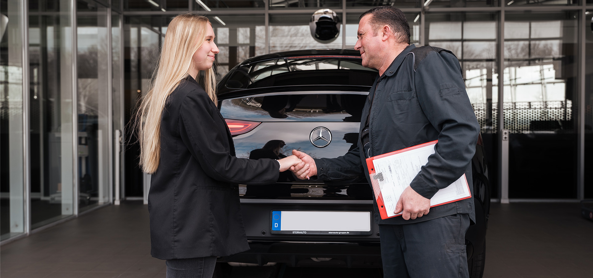 Servicetechniker und Kundin stehen vor Auto