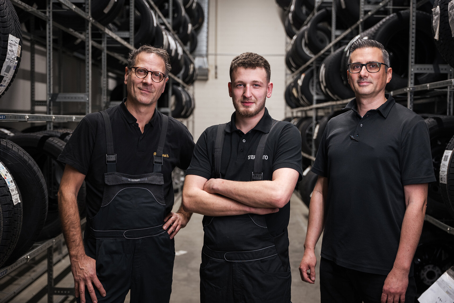 3 Mechaniker stehen im Reifenlager